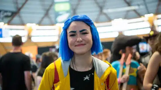Coraline Jones cosplayer with blue hair and a yellow raincoat at Oz Comic-Con Sydney in 2019